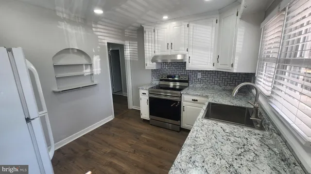 a kitchen with granite countertop a refrigerator stove and sink