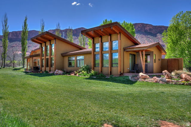 425 Amber Lane Moab, UT 84532 - Photo 2 of 27 Back of house with stucco siding, a yard, and a mountain view
