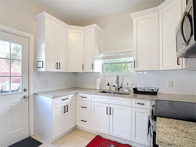 a kitchen with granite countertop white cabinets sink and stainless steel appliances
