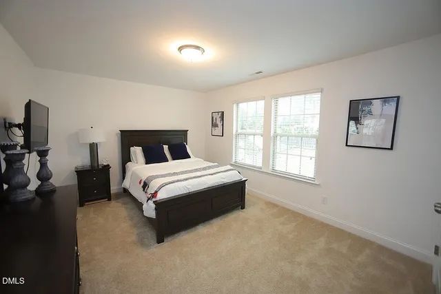 a bedroom with a bed and flat tv screen on the dresser