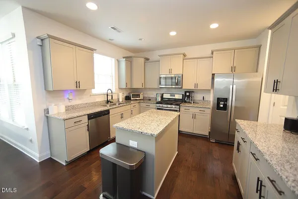 a kitchen with a refrigerator a sink a stove a microwave a center island and cabinets