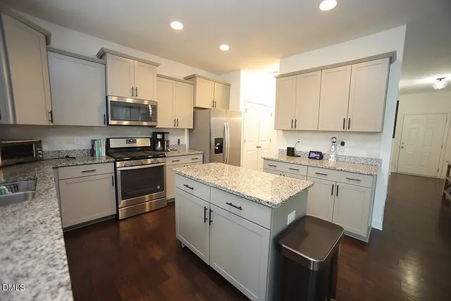 a kitchen with granite countertop white cabinets sink and stainless steel appliances