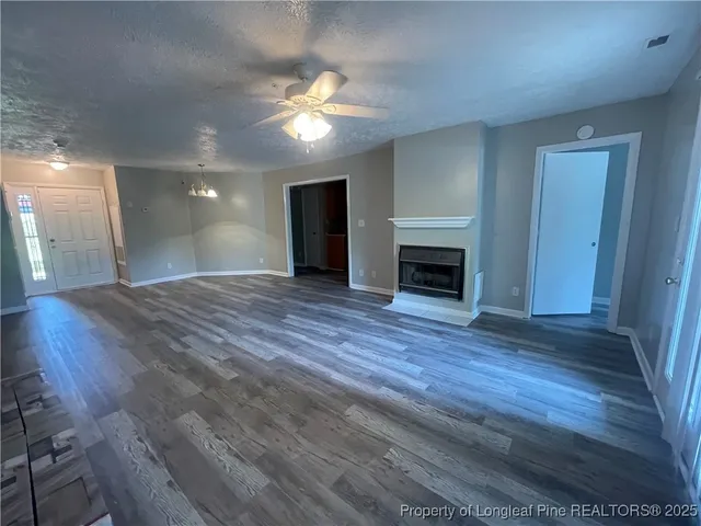 a view of a livingroom with a fireplace wooden floor and chandelier