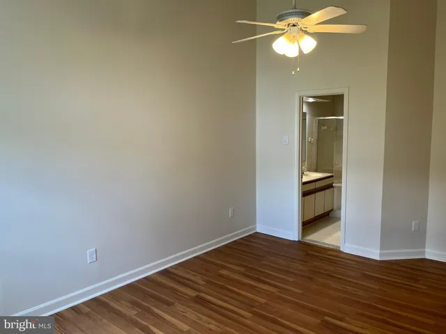 a view of an empty room with wooden floor and a bathroom