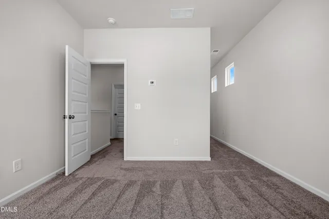 an empty room with windows and entrance to other room