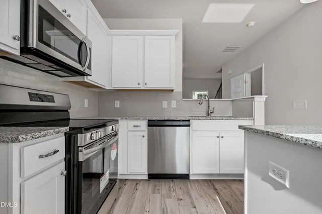 a kitchen with stainless steel appliances granite countertop a stove a sink and a microwave