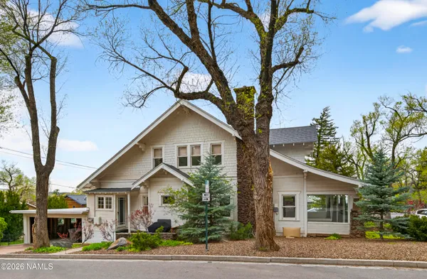 a view of a white house next to a road and trees