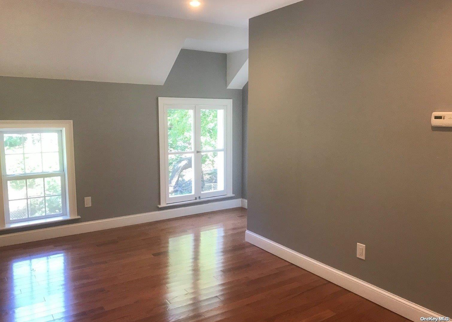 1639 B Cedar Swamp Road Glen Head, NY 11545 - Photo 1 of 1 an empty room with wooden floor and windows