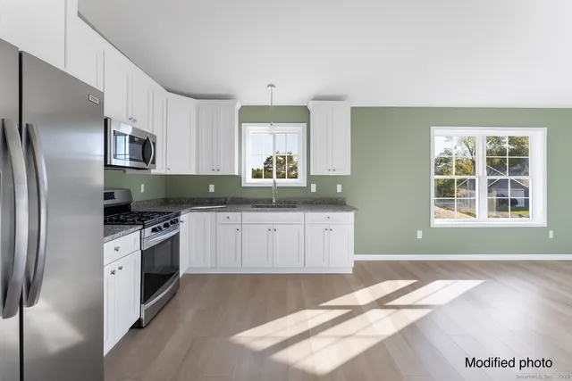 a kitchen with granite countertop stainless steel appliances a sink cabinets and a window