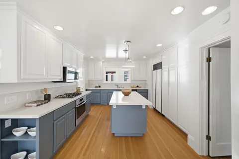 a large kitchen with stainless steel appliances granite countertop a lot of counter space and wooden floor