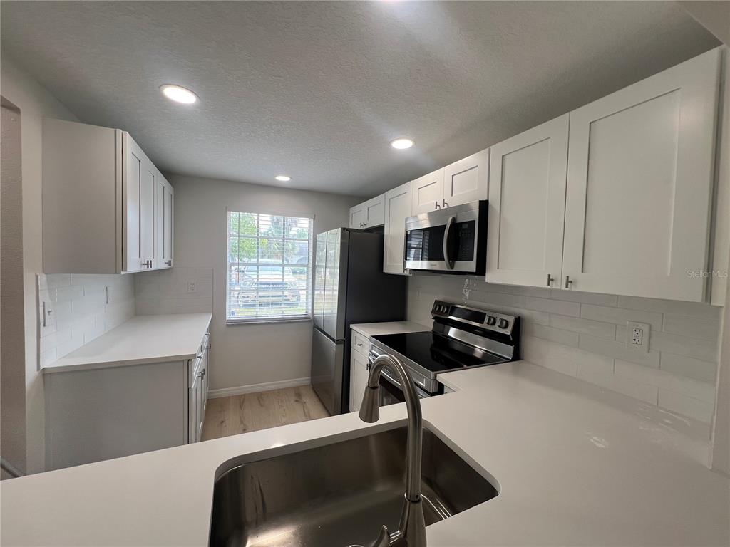 4223 Sheldon Place, Unit 23 New Port Richey, FL 34652 - Photo 3 of 13 a kitchen with a refrigerator a stove a microwave and cabinets