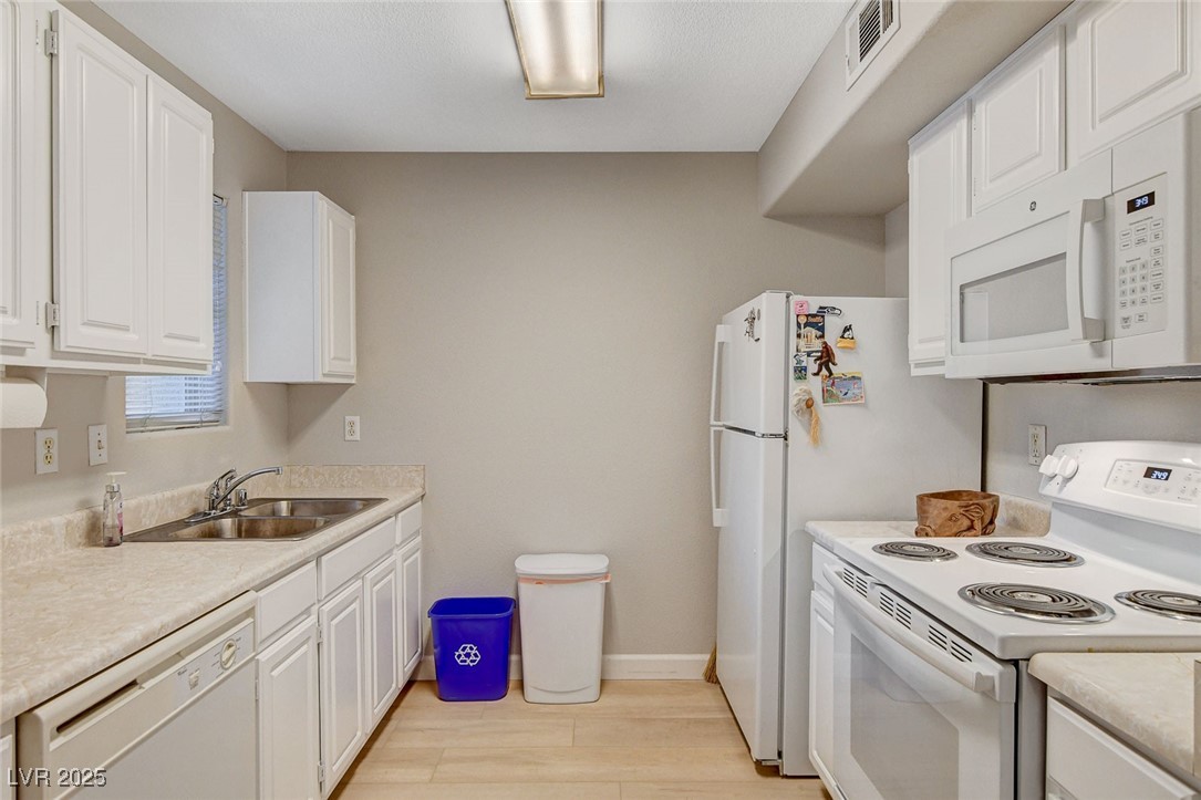 555 East Silverado Ranch Boulevard, Unit 1172 Las Vegas, NV 89183 - Photo 17 of 29 Kitchen with white appliances, white cabinets, light countertops, and light wood-style flooring