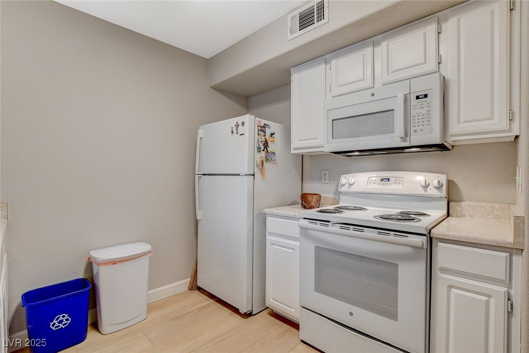 555 East Silverado Ranch Boulevard, Unit 1172 Las Vegas, NV 89183 - Photo 19 of 29 Kitchen featuring white appliances, light countertops, white cabinetry, and light wood-style flooring