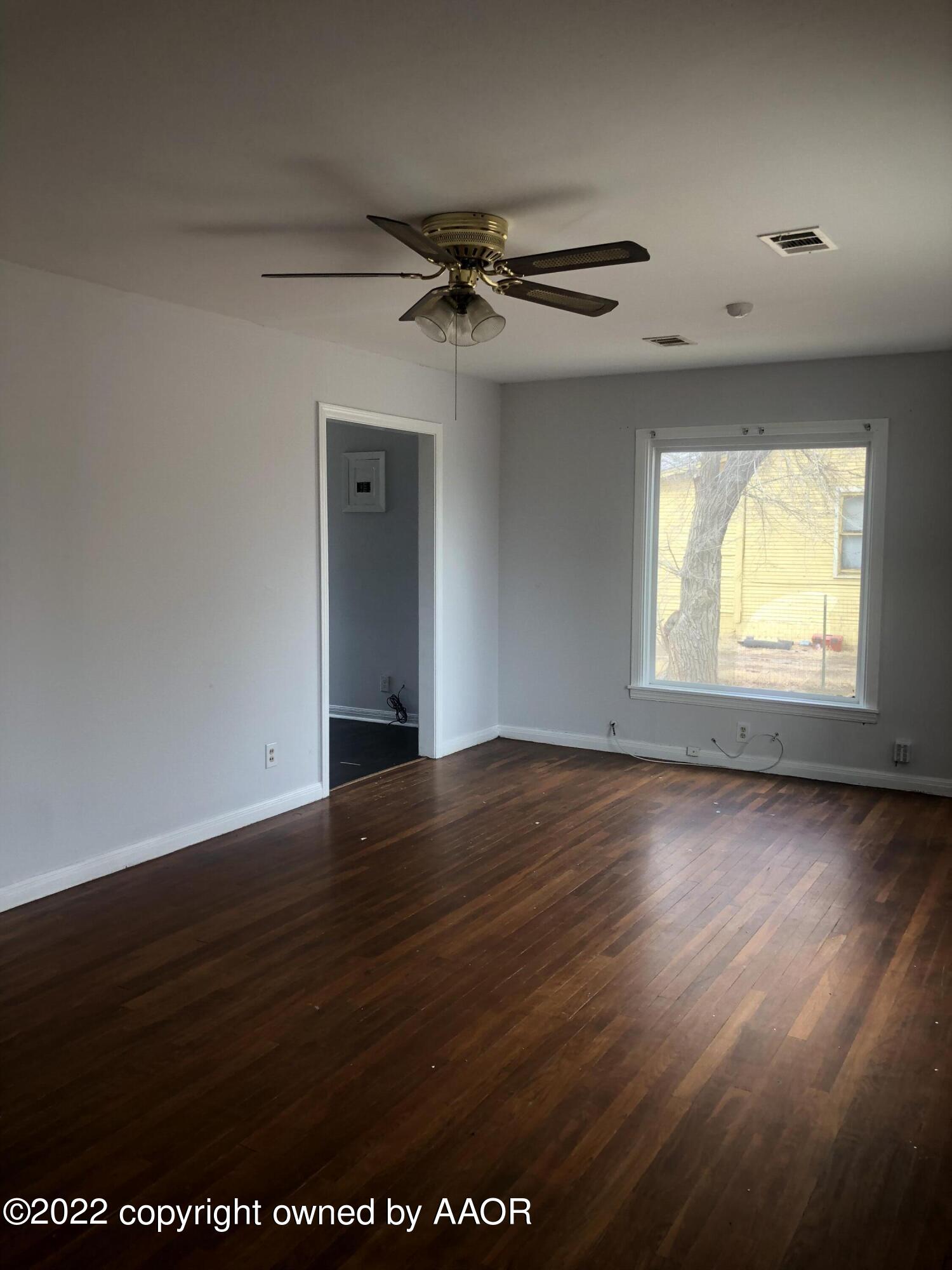 4110 South Polk Street Amarillo, TX 79110 - Photo 6 of 13 an empty room with wooden floor a ceiling fan and windows