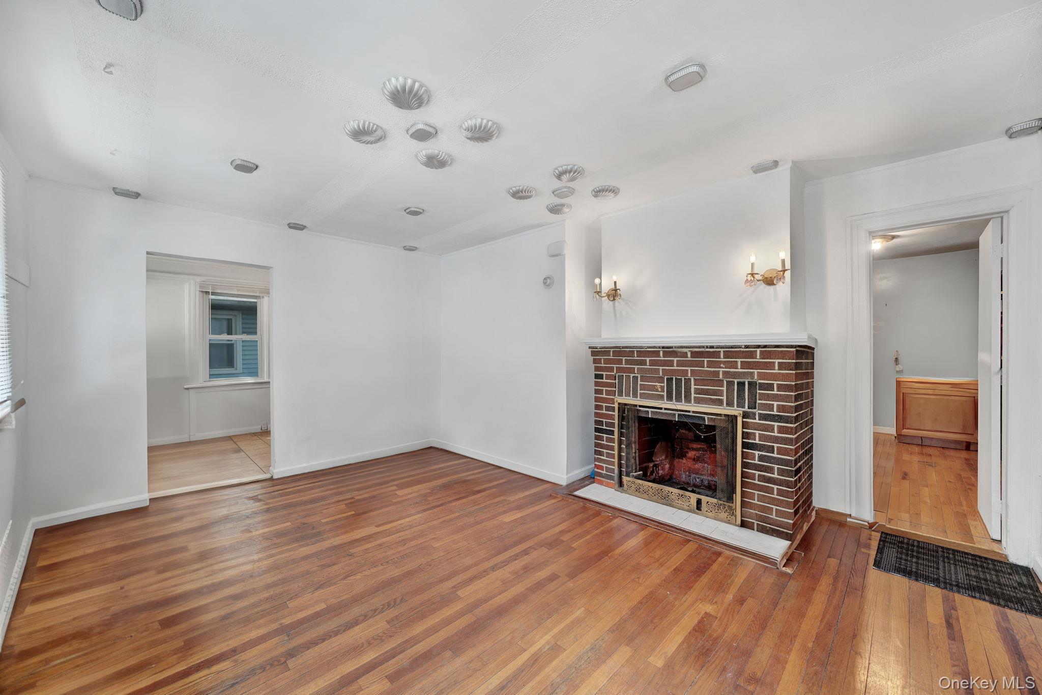 295 Washington Street Hempstead, NY 11550 - Photo 3 of 17 an empty room with wooden floor fireplace and windows