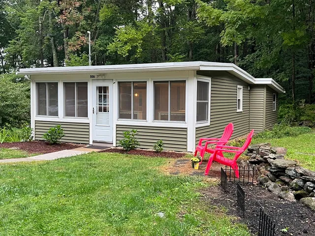 a backyard of a house with table and chairs wooden fence