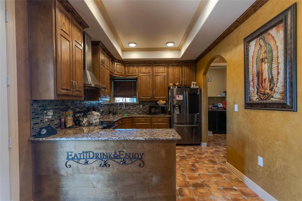 8900 Holly Road Alvarado, TX 76009 - Photo 7 of 17 Wood-finish cabinetry, granite countertops, and a mosaic tile backsplash