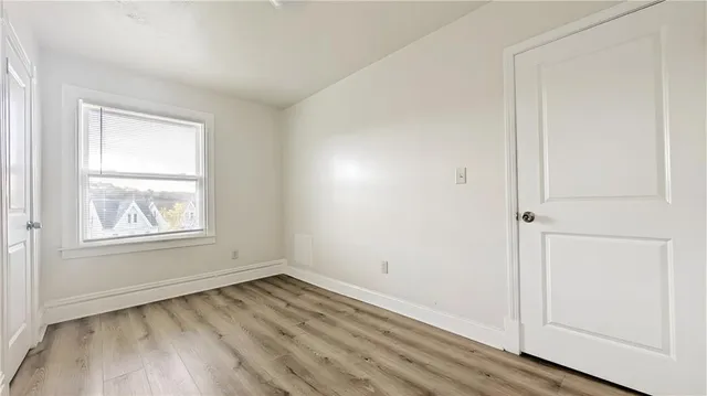 an empty room with wooden floor closet and windows