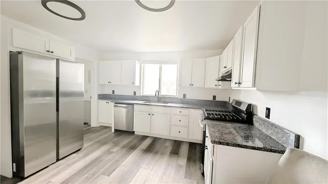 a kitchen with granite countertop a refrigerator sink and cabinets