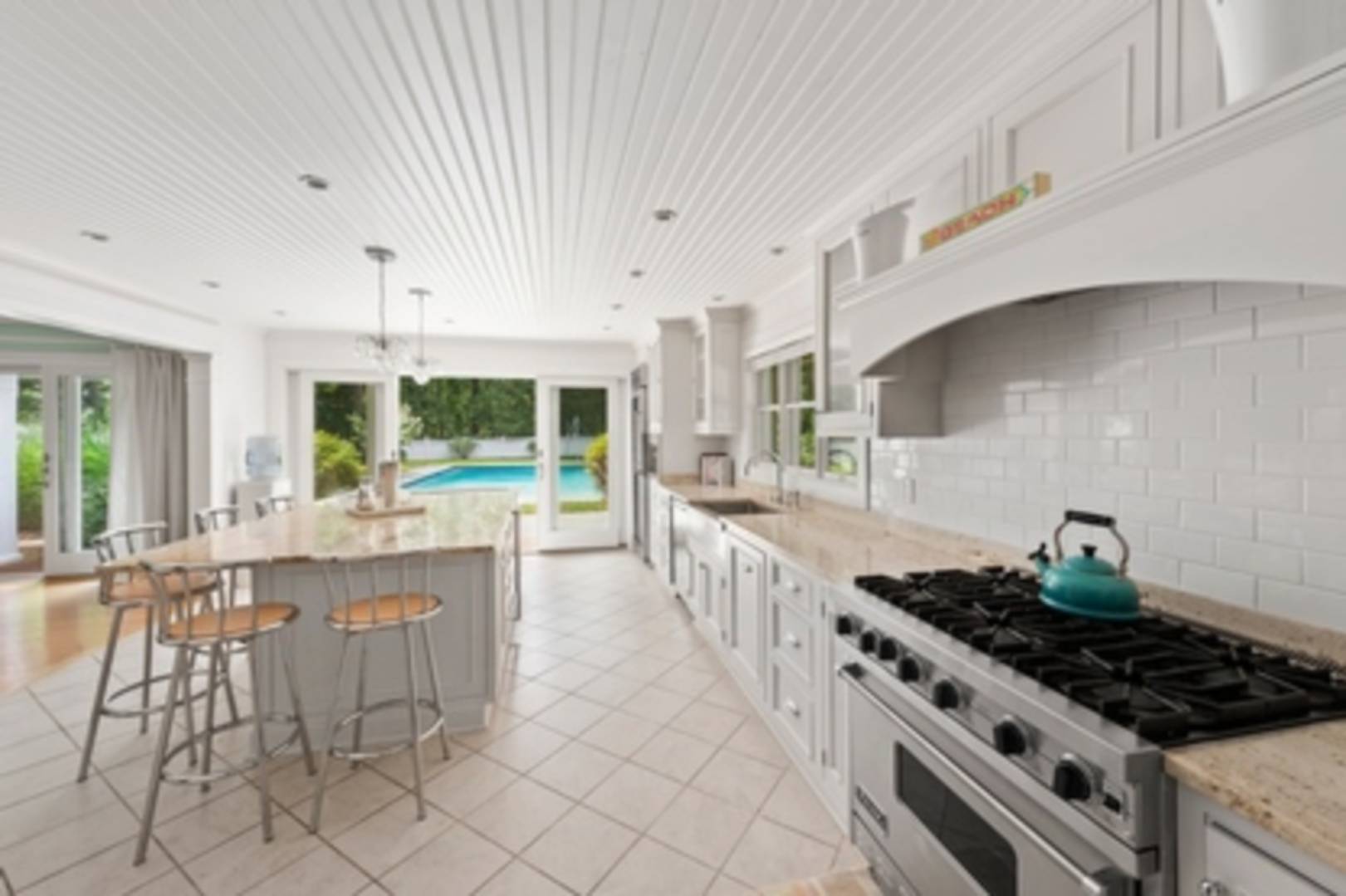 25 East Gate Road Wainscott, NY 11975 - Photo 3 of 13 a kitchen with stainless steel appliances a white stove top oven and white cabinets next to a window