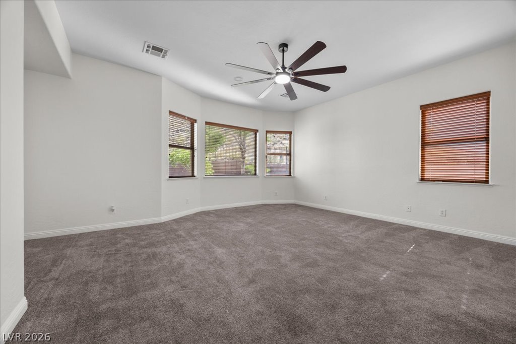 2125 De Rouge Avenue Henderson, NV 89044 - Photo 9 of 96 A spacious room offers plush carpeting and ample natural light through multiple windows, perfect for comfortable living.