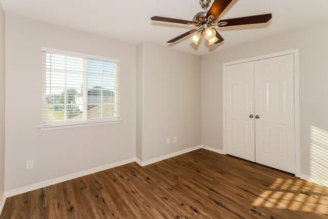 a view of empty room with wooden floor and fan