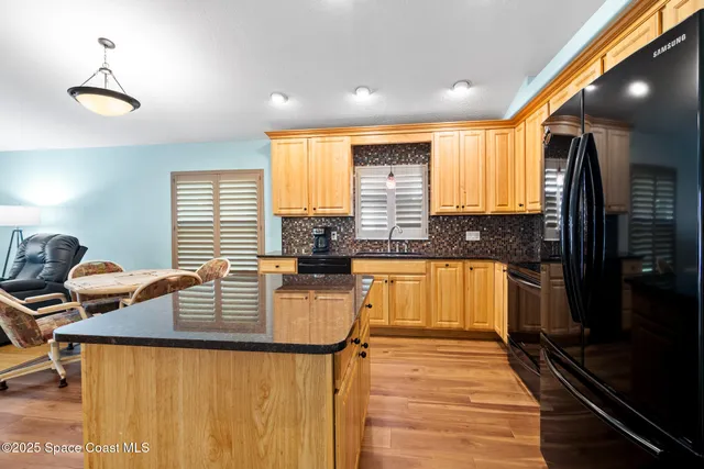 a kitchen with stainless steel appliances granite countertop sink refrigerator and window