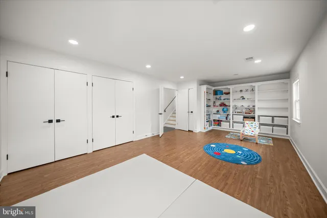 a view of an empty room with kitchen and window