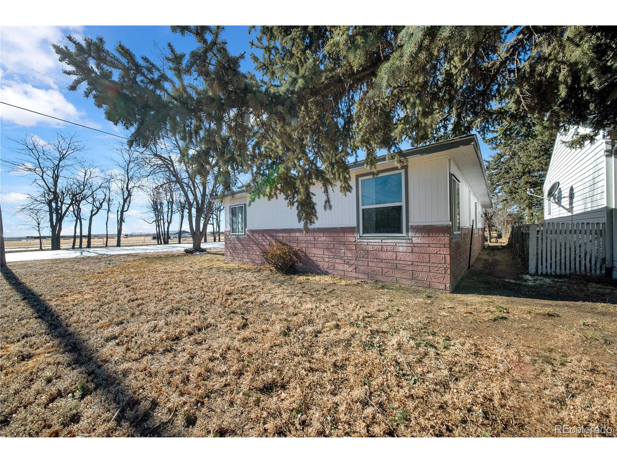 701 4th Street Akron, CO 80720 - Photo 7 of 26 a backyard of a house with large trees and wooden fence