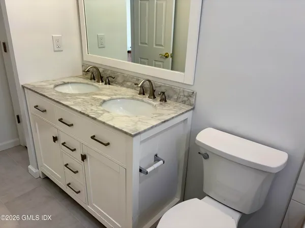 a bathroom with a granite countertop toilet sink and mirror