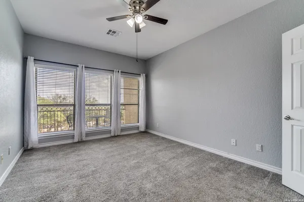 an empty room with windows and chandelier fan