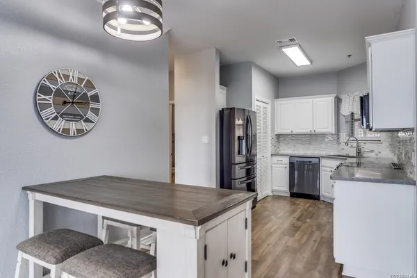 a kitchen with stainless steel appliances granite countertop a refrigerator a stove and a sink