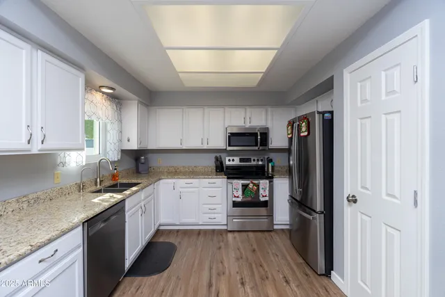 a kitchen with a refrigerator a sink dishwasher and a stove top oven with wooden floor