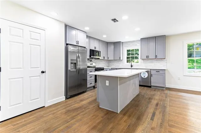 a kitchen with wooden floors stainless steel appliances and a window