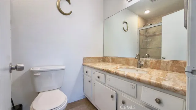 a bathroom with a granite countertop sink a toilet and a mirror