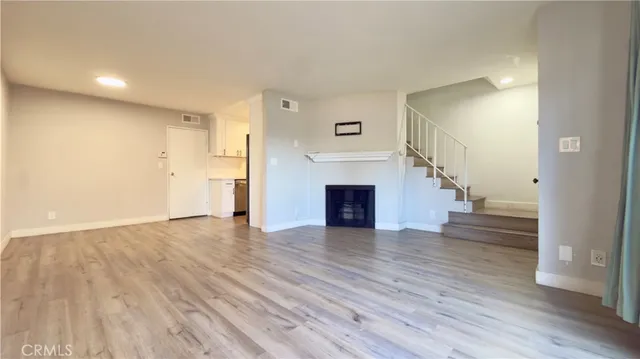 a view of empty room with wooden floor and fireplace