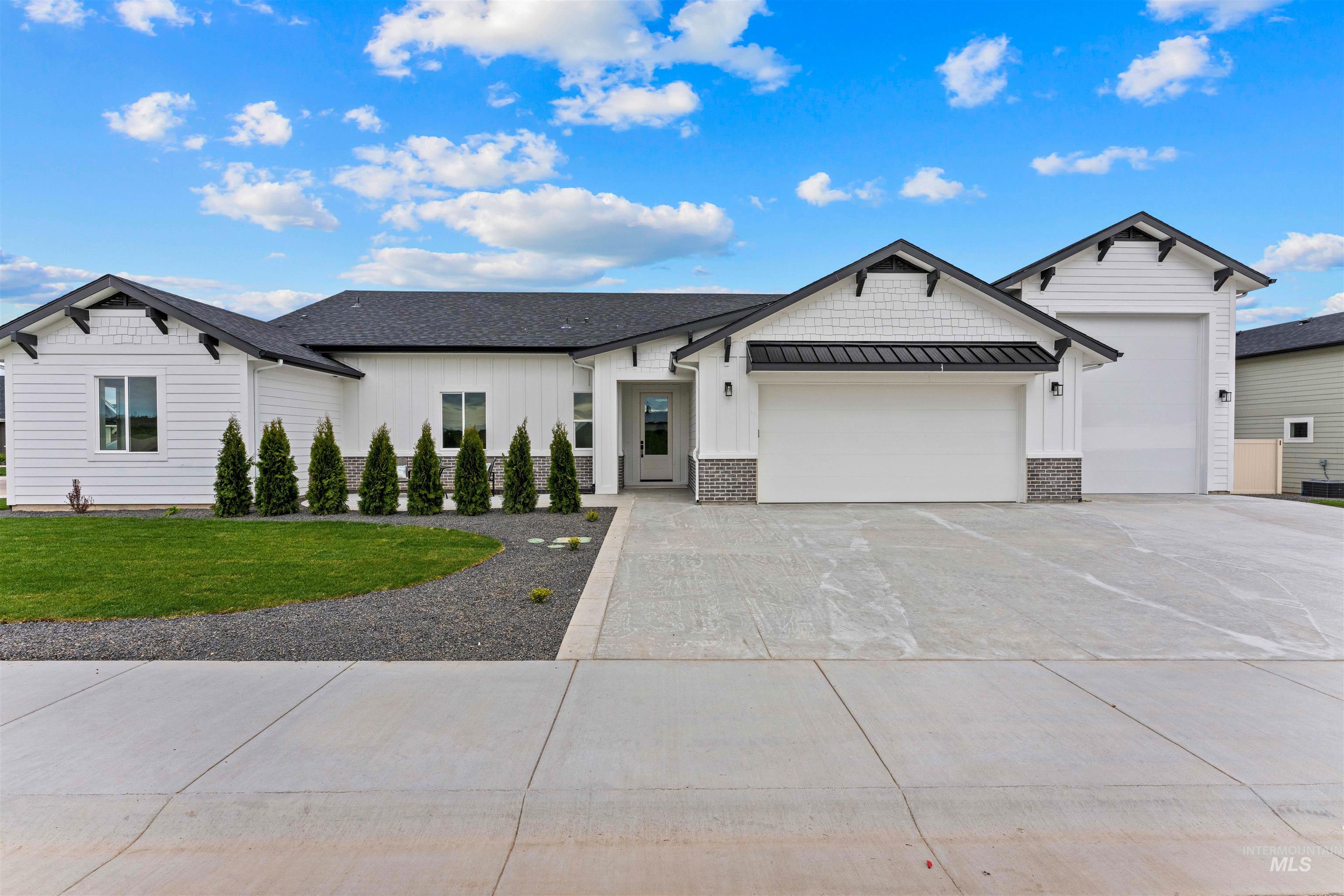 Modern farmhouse style home with board and batten siding, a standing seam roof, and concrete driveway