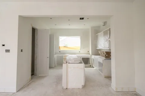 a view of an empty room and a kitchen with furniture wooden floor and windows