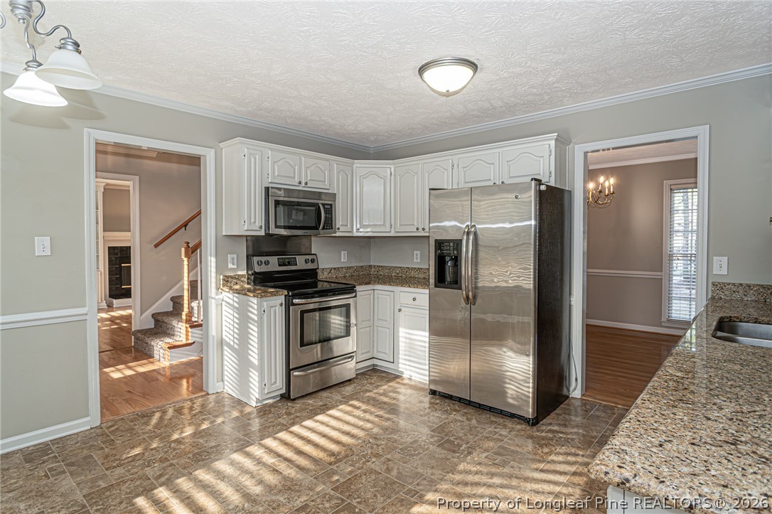 7787 Trappers Road Fayetteville, NC 28311 - Photo 13 of 47 a kitchen with granite countertop a refrigerator and a stove top oven