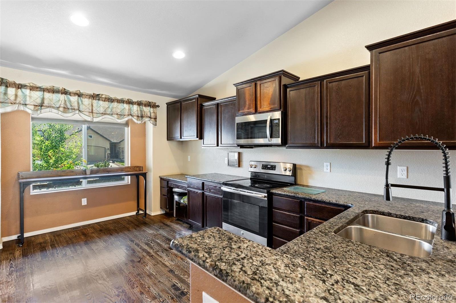2556 Hannah Ridge Drive Colorado Springs, CO 80922 - Photo 4 of 39 a kitchen with granite countertop a stove a sink and a microwave