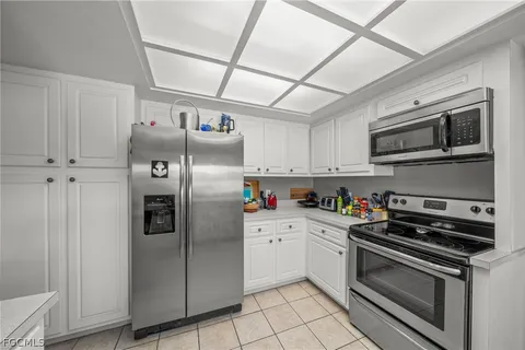 a kitchen with granite countertop a refrigerator and a stove top oven