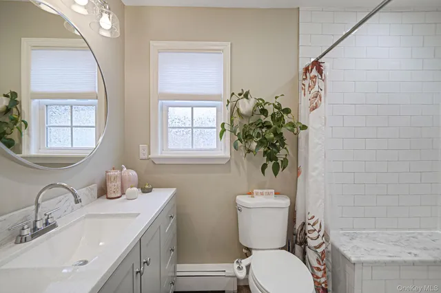 a bathroom with a toilet a sink a mirror a vanity and window