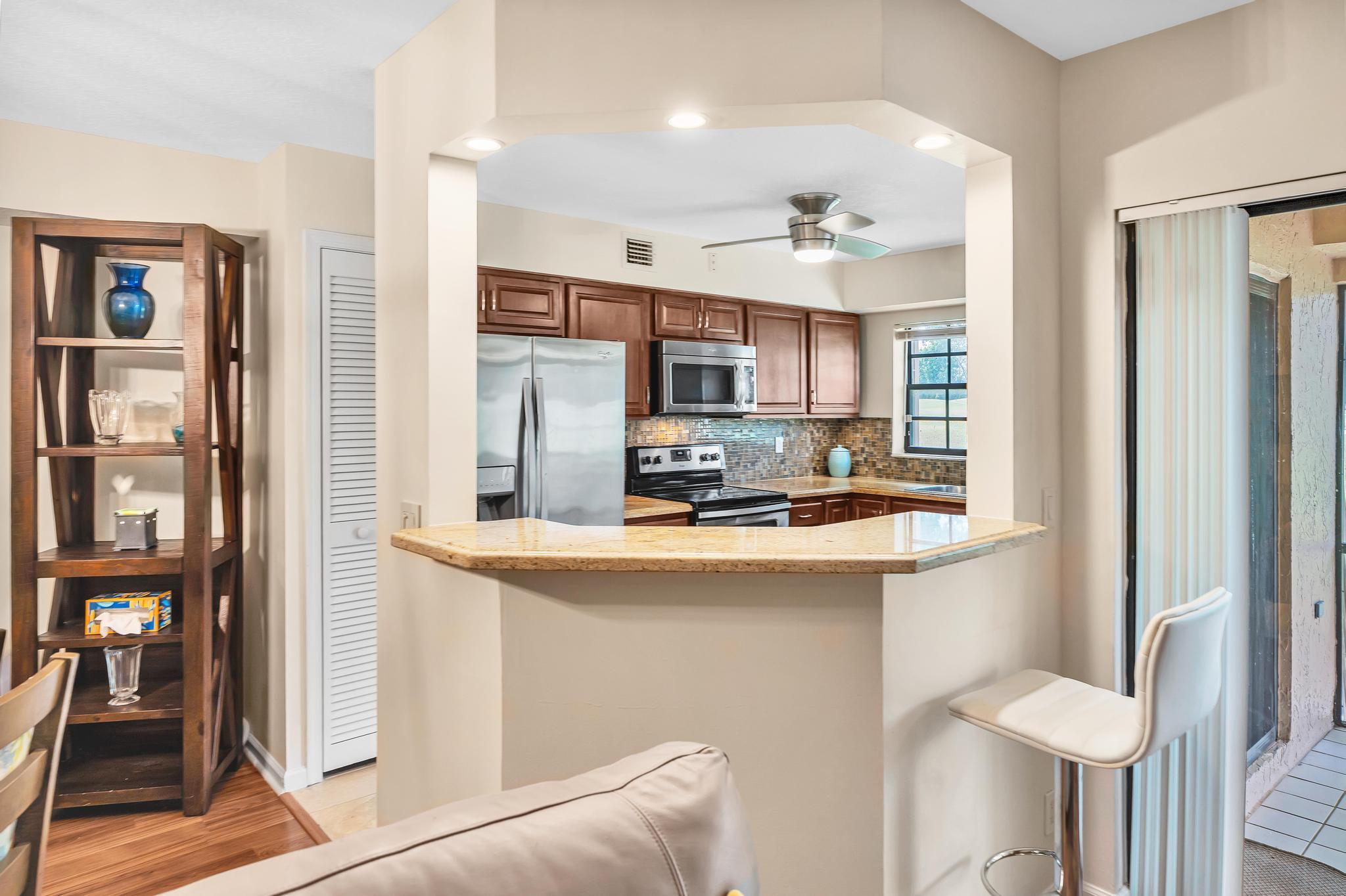 17372 Boca Club Boulevard, Unit 405 Boca Raton, FL 33487 - Photo 25 of 74 a kitchen with stainless steel appliances granite countertop a refrigerator and a stove top oven