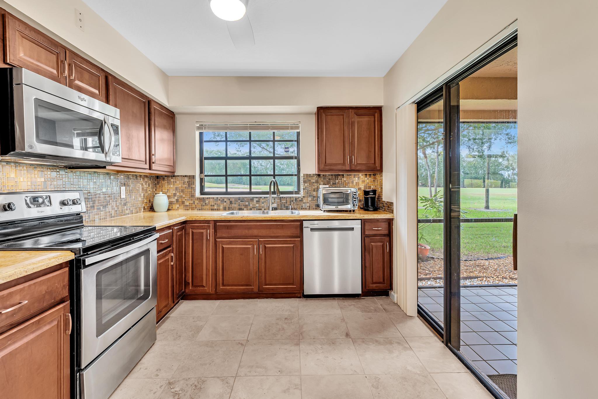 17372 Boca Club Boulevard, Unit 405 Boca Raton, FL 33487 - Photo 28 of 74 a kitchen with a sink stove top oven and cabinets