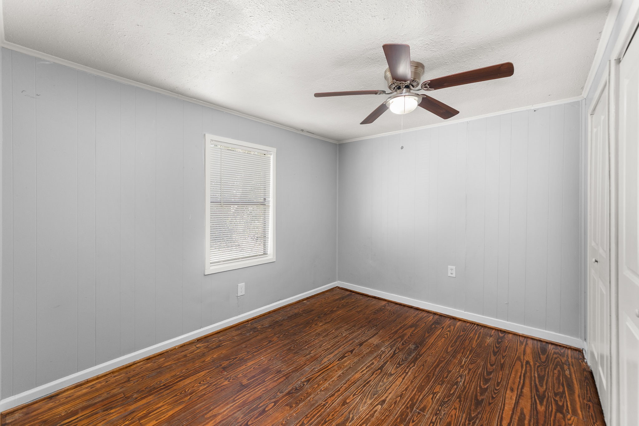 203 South Fig Street Sweeny, TX 77480 - Photo 17 of 20 Cozy third bedroom featuring stylish gray walls, refinished wood floors, and a ceiling fan for comfort. Perfect for relaxation or a home office.