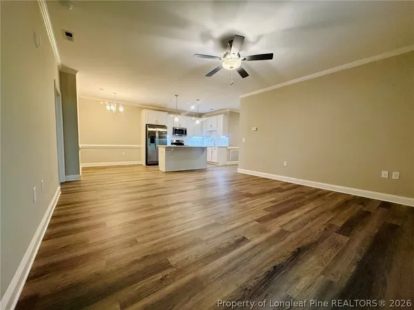 a view of empty room with wooden floor and fan