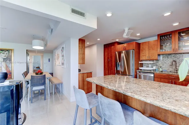 a large kitchen with stainless steel appliances kitchen island granite countertop a table chairs in it