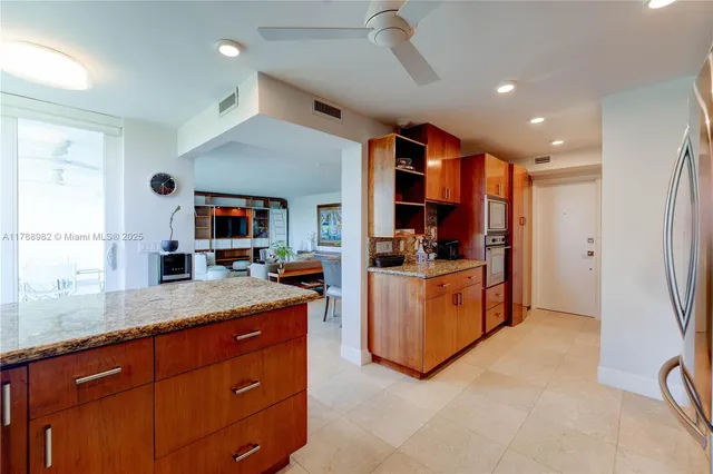 a kitchen with granite countertop a refrigerator and a stove top oven