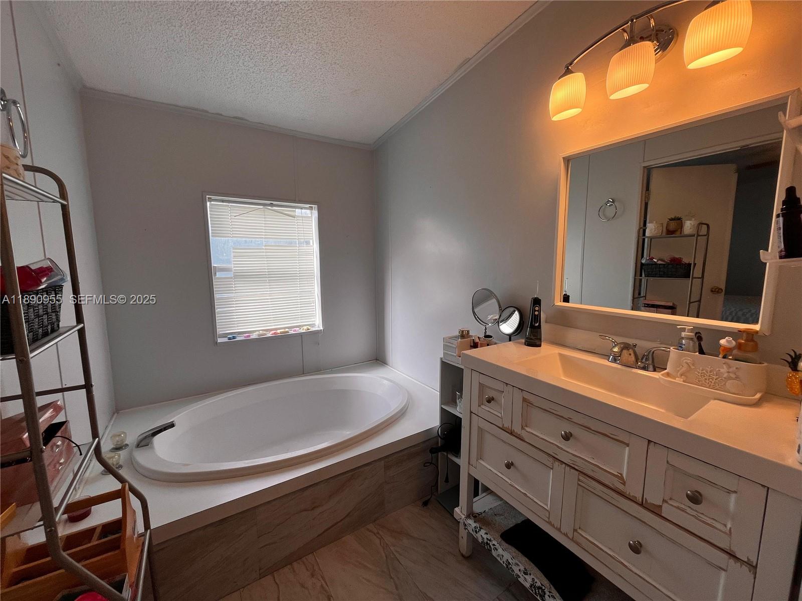 909 Southwest 131st Way Davie, FL 33325 - Photo 14 of 36 a bathroom with a tub sink and mirror