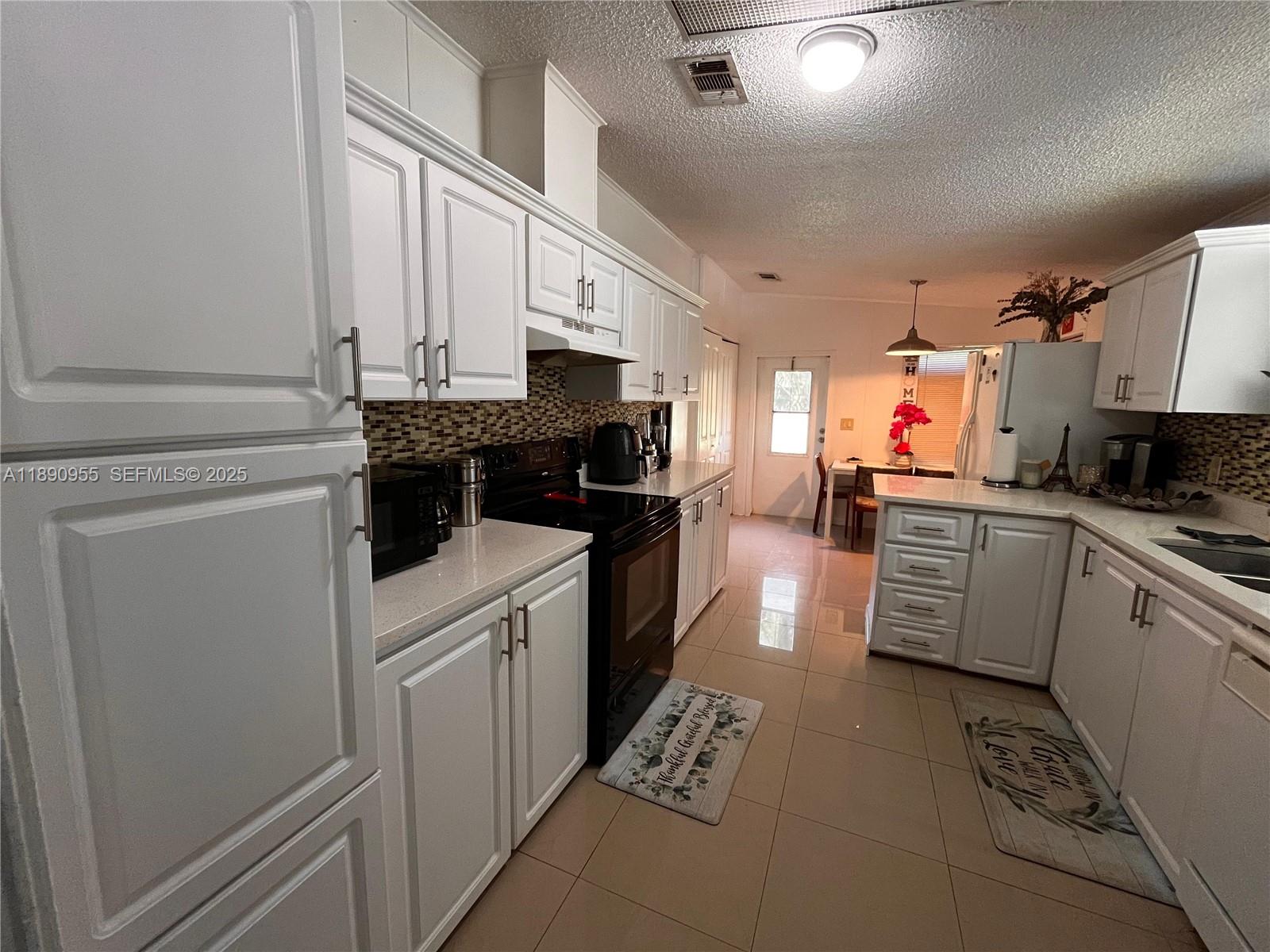 909 Southwest 131st Way Davie, FL 33325 - Photo 2 of 36 a kitchen with stainless steel appliances white cabinets and a stove